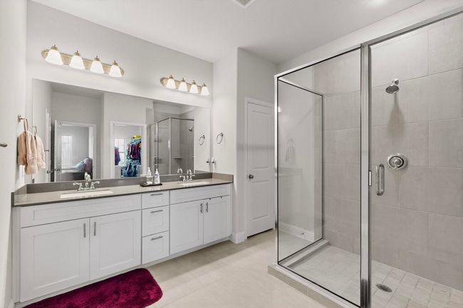Bathroom featuring a stall shower, double vanity, a spacious closet, and tile patterned flooring | Image 22