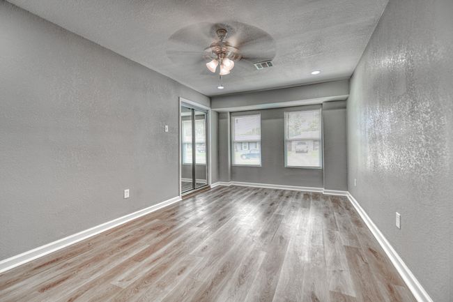 Empty room featuring a textured wall, ceiling fan, wood finished floors, and a textured ceiling | Image 15