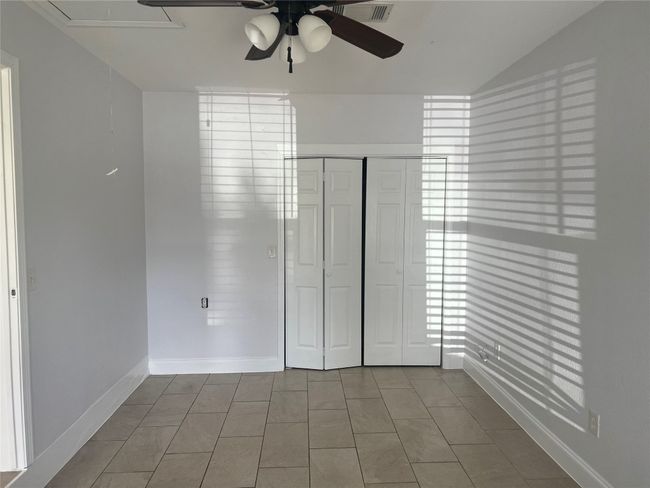 Unfurnished bedroom featuring attic access, tile patterned flooring, a closet, a ceiling fan, and vaulted ceiling | Image 11