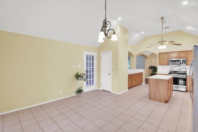 Kitchen with stainless steel appliances, lofted ceiling, arched walkways, light countertops, and light tile patterned flooring | Image 21