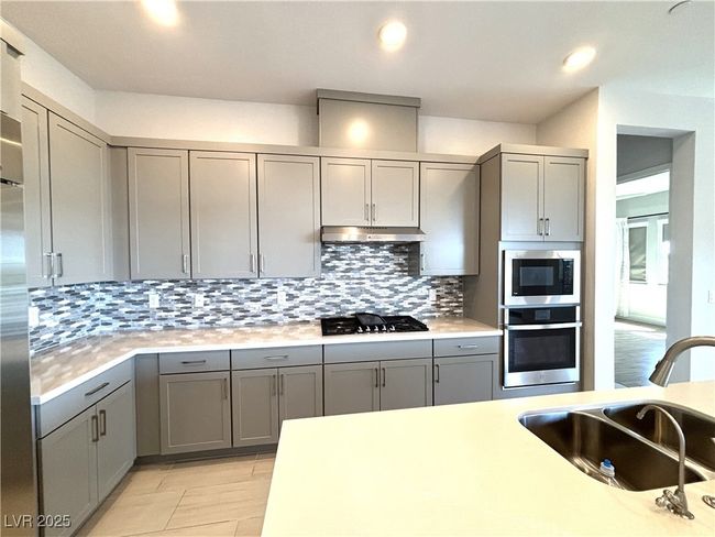 Kitchen with gray cabinetry, a sink, appliances with stainless steel finishes, and decorative backsplash | Image 16