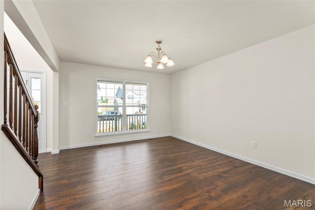 Spare room featuring a chandelier, stairway, and dark wood-style flooring | Image 4