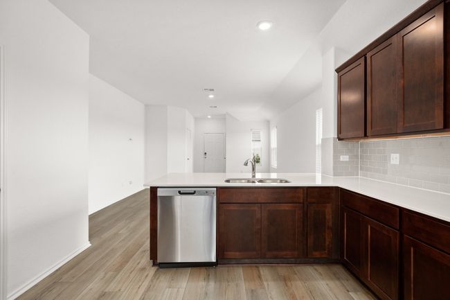 Kitchen with stainless steel dishwasher, a sink, a peninsula, light countertops, and light wood-type flooring | Image 9