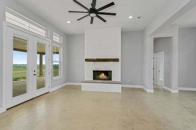 Unfurnished living room with french doors, concrete flooring, baseboards, a ceiling fan, and recessed lighting | Image 12