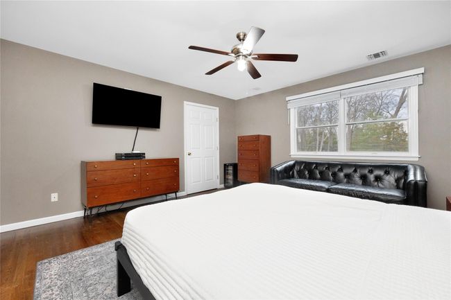 Bedroom with visible vents, baseboards, dark wood-style floors, and ceiling fan | Image 13