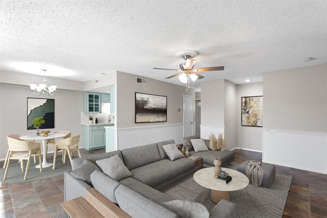 Living room with a wainscoted wall, ceiling fan with notable chandelier, a textured ceiling, and visible vents | Image 11