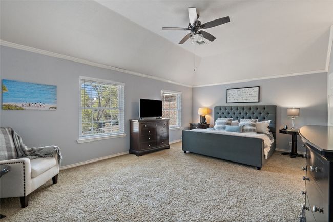 Carpeted bedroom with a ceiling fan, crown molding, baseboards, and vaulted ceiling | Image 22