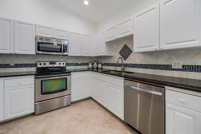 Kitchen with white cabinetry, stainless steel appliances, sink, and decorative backsplash | Image 6
