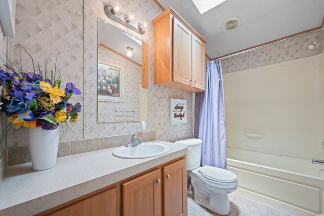 Bathroom with wallpapered walls, shower / bath combination with curtain, vanity, toilet, and tile patterned flooring | Image 24
