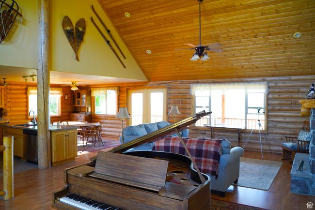 Living area featuring rustic walls, ceiling fan, high vaulted ceiling, wood finished floors, and wooden ceiling | Image 9
