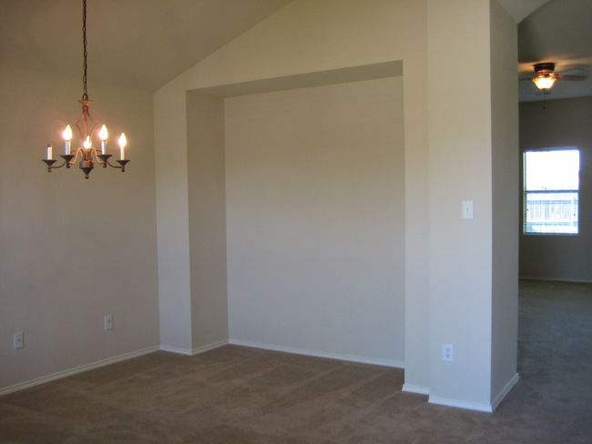 Empty room featuring carpet flooring, a chandelier, vaulted ceiling, and a ceiling fan | Image 9