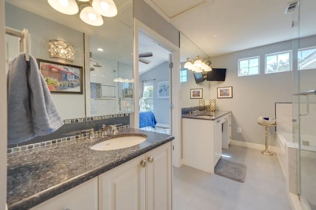 Bathroom featuring a shower stall, two vanities, a bath, and lofted ceiling | Image 22