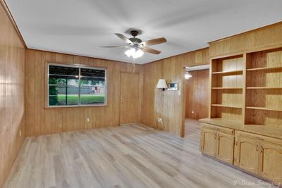 Spare room with light wood-type flooring, wood walls, and ceiling fan | Image 3