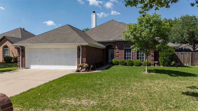 Ranch-style house with fence, a front lawn, brick siding, and a garage | Image 37