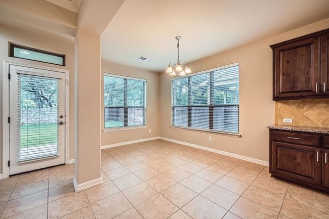 Unfurnished dining area featuring healthy amount of natural light, light tile patterned floors, and a chandelier | Image 13