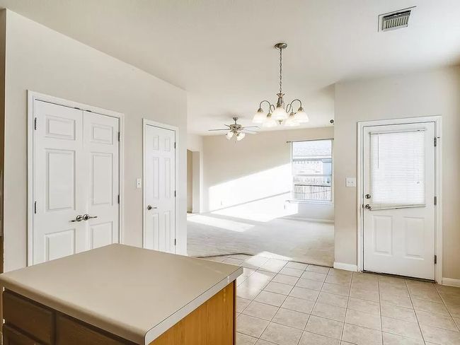 Kitchen featuring a chandelier, light colored carpet, light tile patterned flooring, pendant lighting, and a center island | Image 9