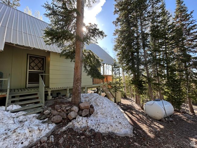 View of home's exterior with a metal roof, stairway, and a wooden deck | Image 40