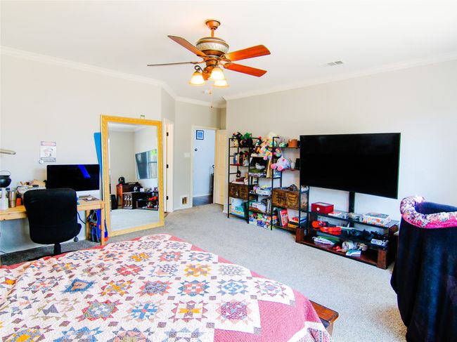 Carpeted bedroom featuring crown molding, ceiling fan, and a desk | Image 9