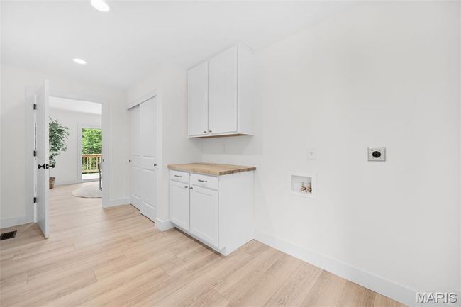 Washroom with electric dryer hookup, hookup for a washing machine, light wood finished floors, recessed lighting, and cabinet space | Image 23