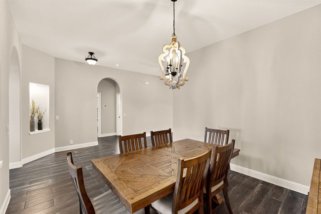 Dining space with arched walkways, dark wood-style floors, a chandelier, and baseboards | Image 20