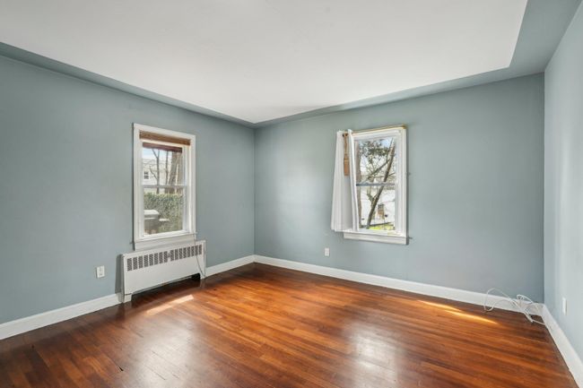 Unfurnished room featuring radiator heating unit, wood finished floors, and baseboards | Image 13