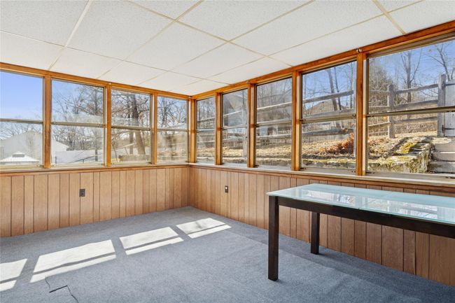 Unfurnished sunroom featuring a paneled ceiling, wood walls, and carpet flooring | Image 26