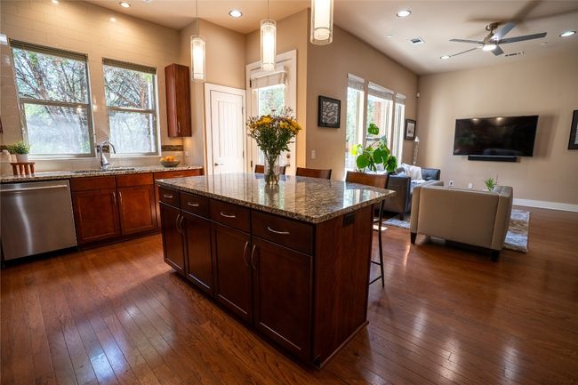 Kitchen featuring dishwasher, open floor plan, dark wood finished floors, a kitchen bar, and recessed lighting | Image 7