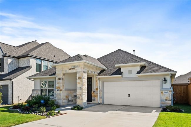 View of front facade with stucco siding, stone siding, concrete driveway, an attached garage, and a shingled roof | Image 32