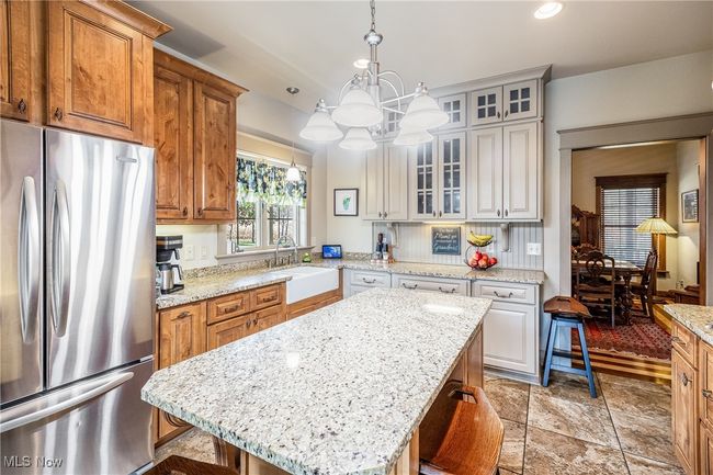 Kitchen featuring a center island, glass insert cabinets, freestanding refrigerator, a sink, and a kitchen bar | Image 23