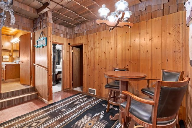 Dining space with wood ceiling, visible vents, a chandelier, and wooden walls | Image 52