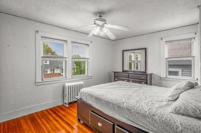 Bedroom featuring ceiling fan, radiator, wood-type flooring, and a textured ceiling | Image 34