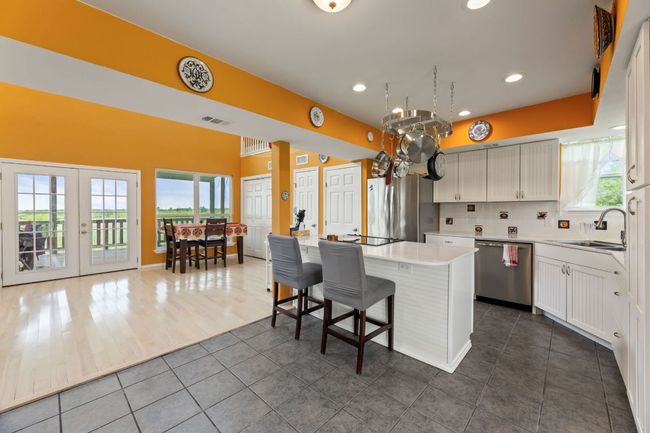 Kitchen featuring a sink, a center island, stainless steel appliances, visible vents, and dark tile patterned flooring | Image 9