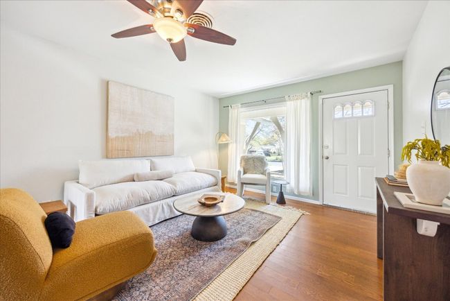 Living area with wood finished floors, baseboards, and ceiling fan | Image 5