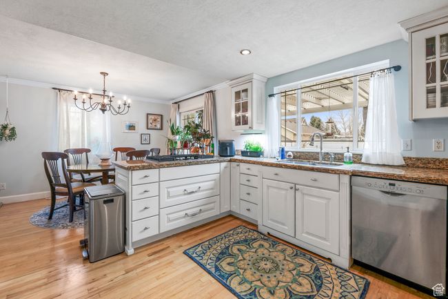 Kitchen featuring white cabinets, light wood-style flooring, appliances with stainless steel finishes, a peninsula, and a sink | Image 13