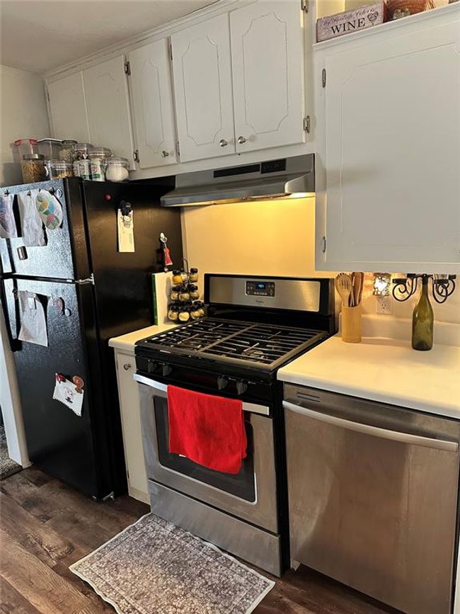 Kitchen featuring under cabinet range hood, white cabinetry, light countertops, appliances with stainless steel finishes, and dark wood-style floors | Image 11