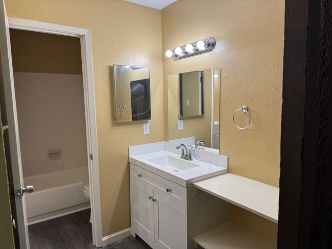 Bathroom with wood finished floors, vanity, and a textured wall | Image 17