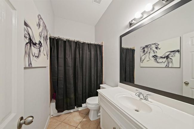 The connected bath offers tile flooring, an extended single sink vanity, designer lighting, and a convenient tub/shower combination. | Image 39
