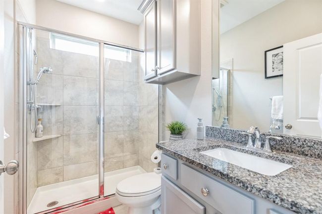 This photo showcases the Next Gen suite bathroom, designed with sleek, modern finishes. It includes a glass-enclosed shower, a beautiful granite countertop, and contemporary fixtures. The neutral tones and abundant lighting enhance the space, creating a bright, airy, and inviting atmosphere. | Image 33