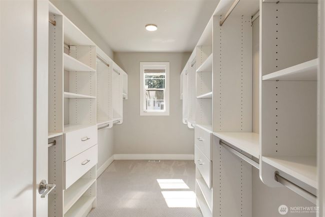 The expansive walk-in closet in the primary suite is outfitted with custom built-ins, ample hanging space, and natural light from a central window. Designed for both function and elegance, it offers a beautifully organized start and finish to each day. | Image 29