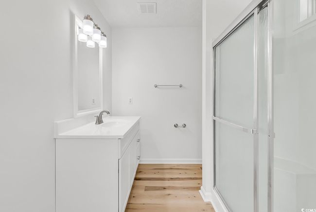 Full bath featuring vanity, baseboards, wood finished floors, a shower with door, and visible vents | Image 17