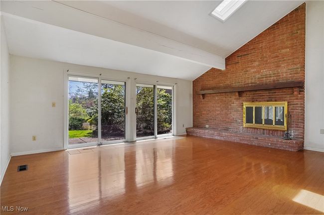 Unfurnished living room featuring baseboards, visible vents, beamed ceiling, wood finished floors, and a fireplace | Image 37