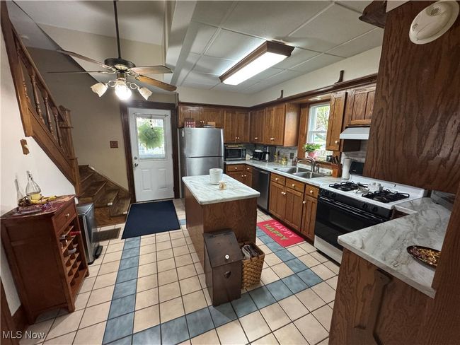 Kitchen featuring a sink, stainless steel appliances, light countertops, a kitchen island, and under cabinet range hood | Image 6