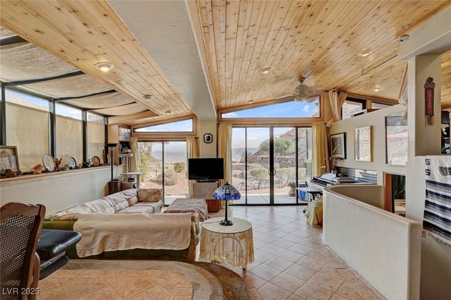 Tiled living room with a ceiling fan, vaulted ceiling, and wood ceiling | Image 19