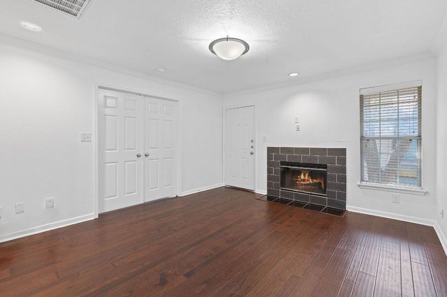 Unfurnished living room with dark wood finished floors, visible vents, baseboards, and ornamental molding | Image 8