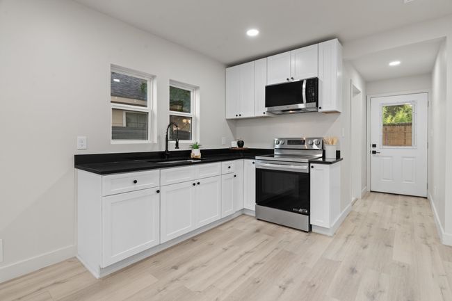 Kitchen featuring appliances with stainless steel finishes, a sink, light wood-style floors, white cabinetry, and recessed lighting | Image 7