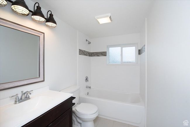 Bathroom with vanity, washtub / shower combination, tile patterned floors, and toilet | Image 26