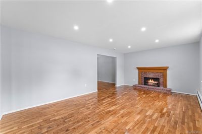 Unfurnished living room featuring light wood-type flooring and a brick fireplace | Image 3