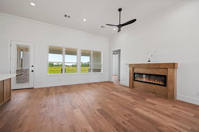 Experience the warmth of this inviting living room, featuring elegant LVP floors, a sleek modern fireplace, and abundant natural light from expansive windows. | Image 21