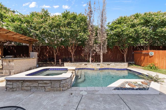 View of swimming pool featuring a fenced backyard, a pergola, and a pool with connected hot tub | Image 40