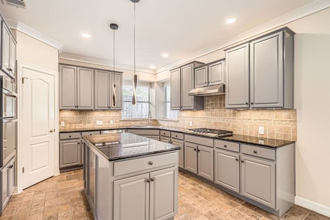 Kitchen featuring a center island, a sink, under cabinet range hood, gray cabinets, and stainless steel gas cooktop | Image 15